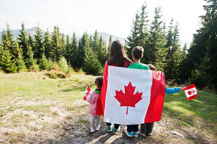 Family walking together through a Canadian forest carrying a Canadian flag